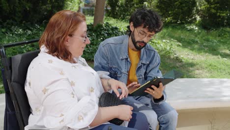 woman in wheelchair with young man using tablet