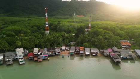 Northern-Koh-lanta-coast-with-wooden-houses-at-shore-and-tropical-palm-trees-in-background,-Thailand---Drone-orbit-shot