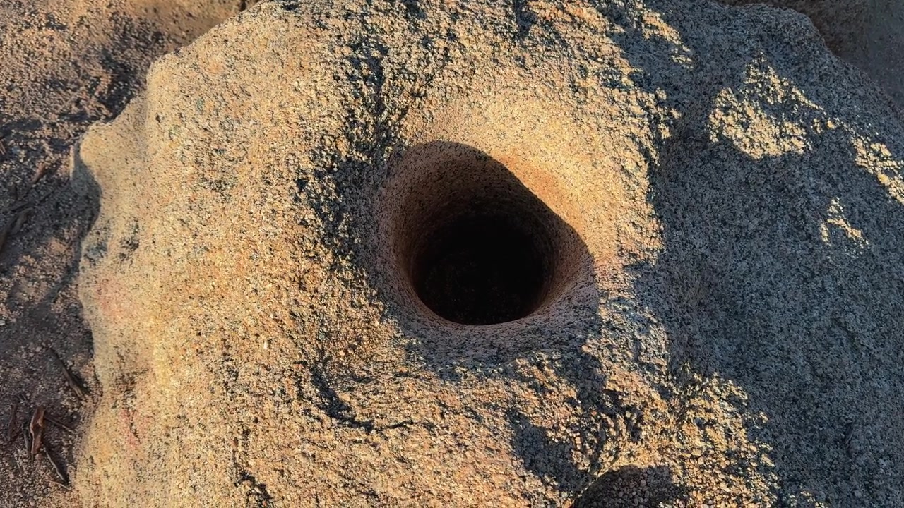 La telecamera si avvicina a un foro circolare in una superficie rocciosa desertica strutturata