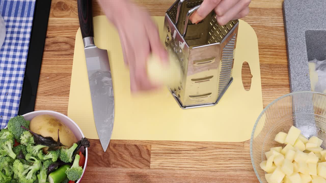 Primo piano di mani che tagliano a cubetti e grattugiano patate in cucina