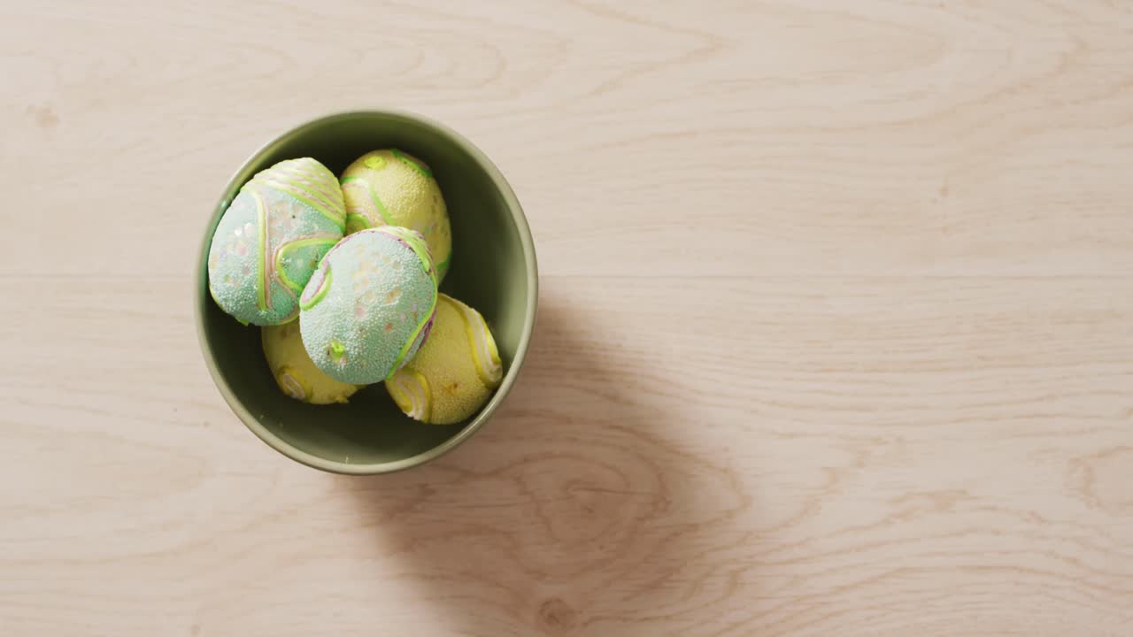 Video of decorated colorful easter eggs in bowl on a wooden surface