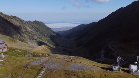 backward cinematic tilt-up of people on mountaintop over transfagarasan, romania