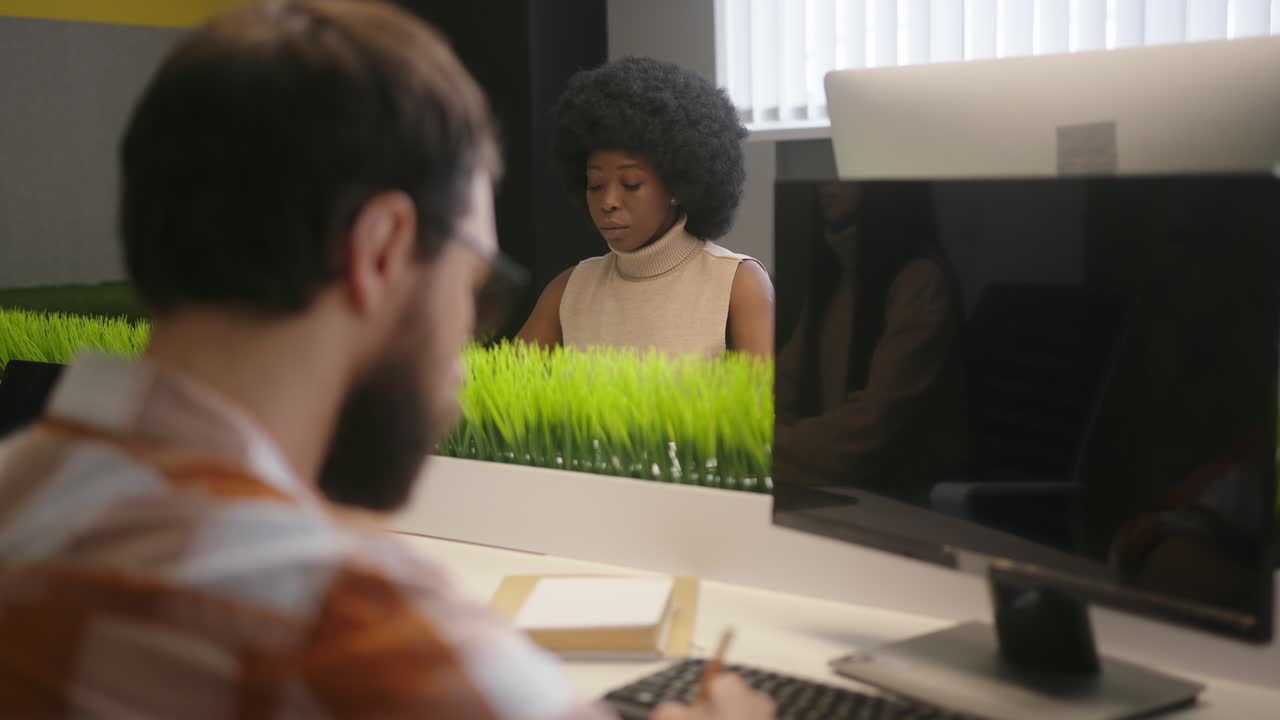 Multinational people sit at desks working on computers