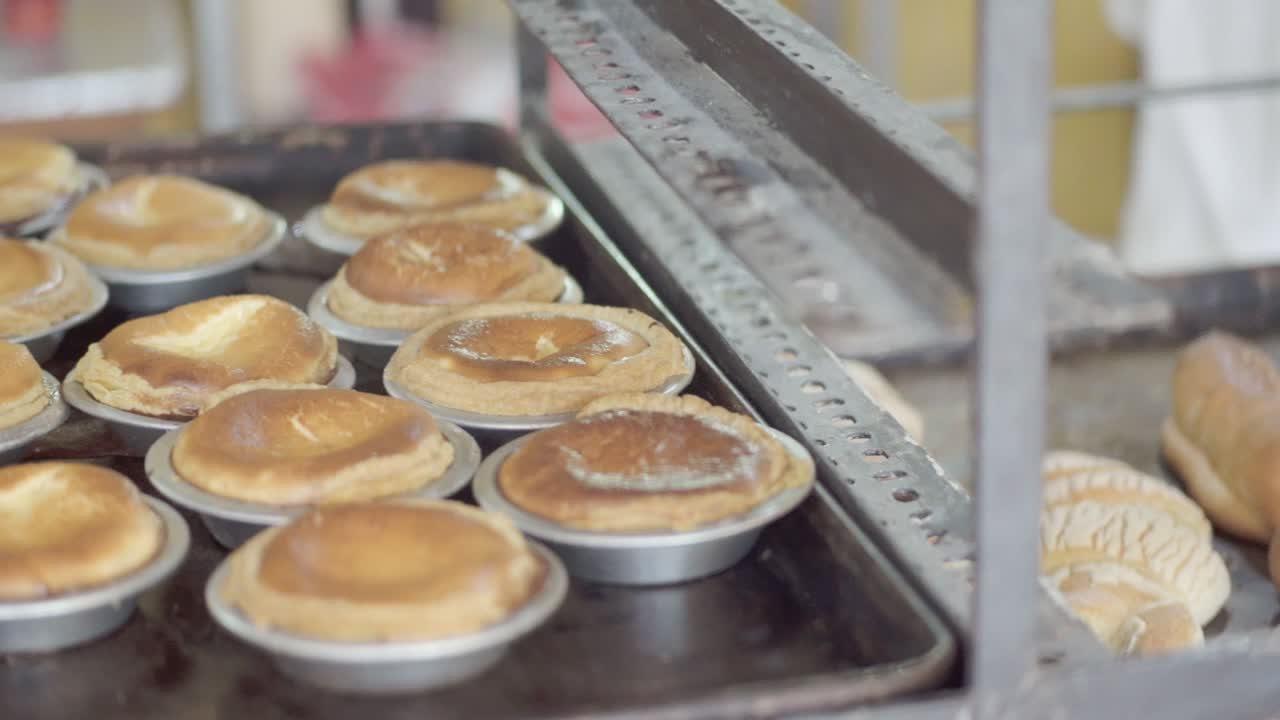 Close-up of multiple trays filled with assorted baked pastries cooling on racks inside a bakery