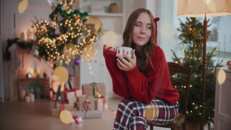 thoughtful woman holding coffee cup on chair during christmas at home