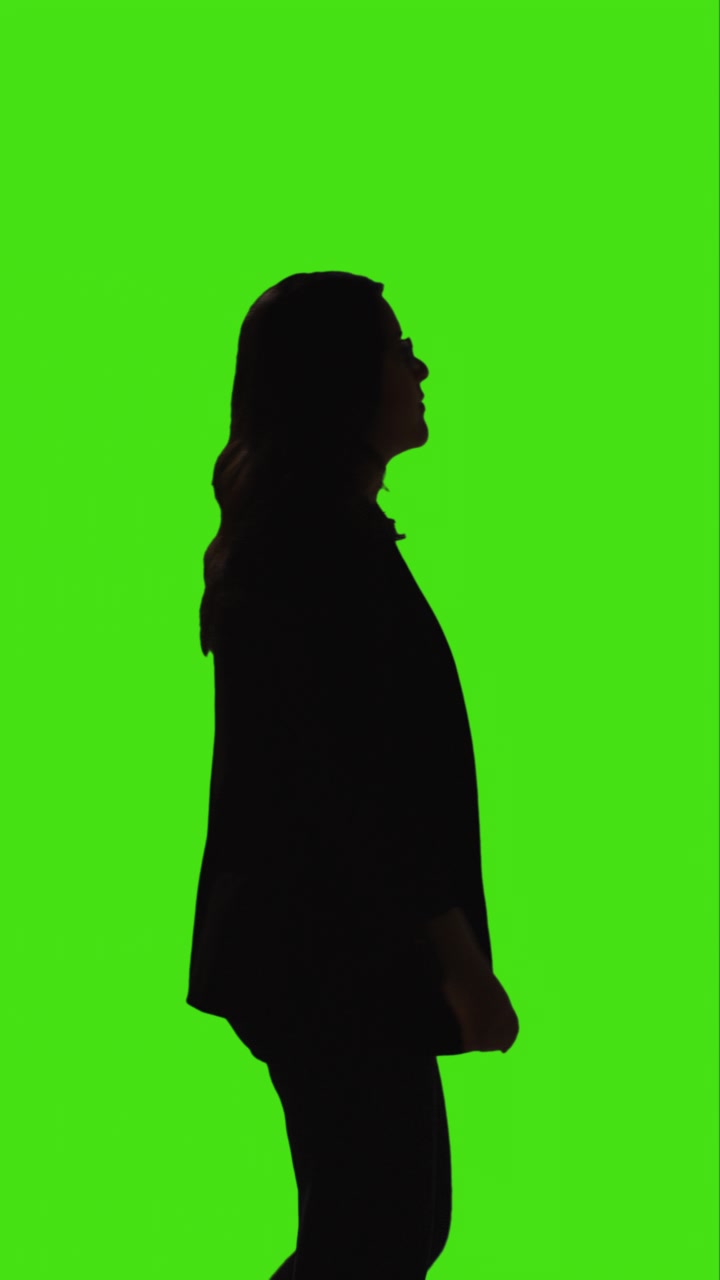 Vertical Video Silhouette Shot Of Businesswoman Wearing Suit Walking Slowly Across Frame Against Green Screen 1