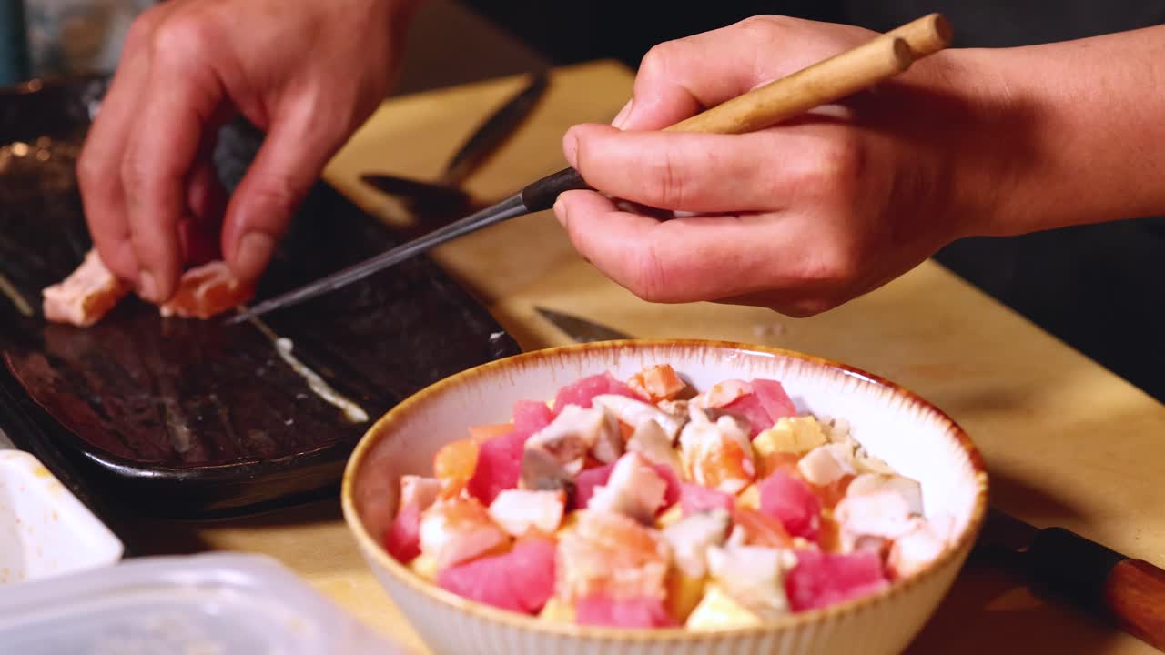 Primo piano di uno chef che usa le bacchette per assemblare una colorata ciotola di chirashi giapponese