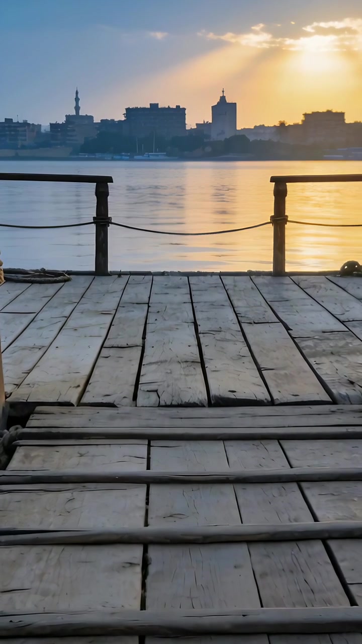 Vertical video: Shifting camera revealing wooden pier at river, with rope, cleat, railing, sunbeams