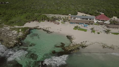 Flyover-a-small-beach-bay-with-turquoise-water-and-a-beach-house