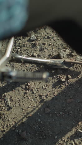 primer plano de un motociclista dejando caer el soporte de la bicicleta para equilibrarla en una superficie de grava