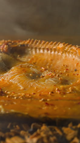 cooking smoked ide fish with seasonings and crispy crust on decayed shavings and charcoals with floating steam in smokehouse macro slow motion