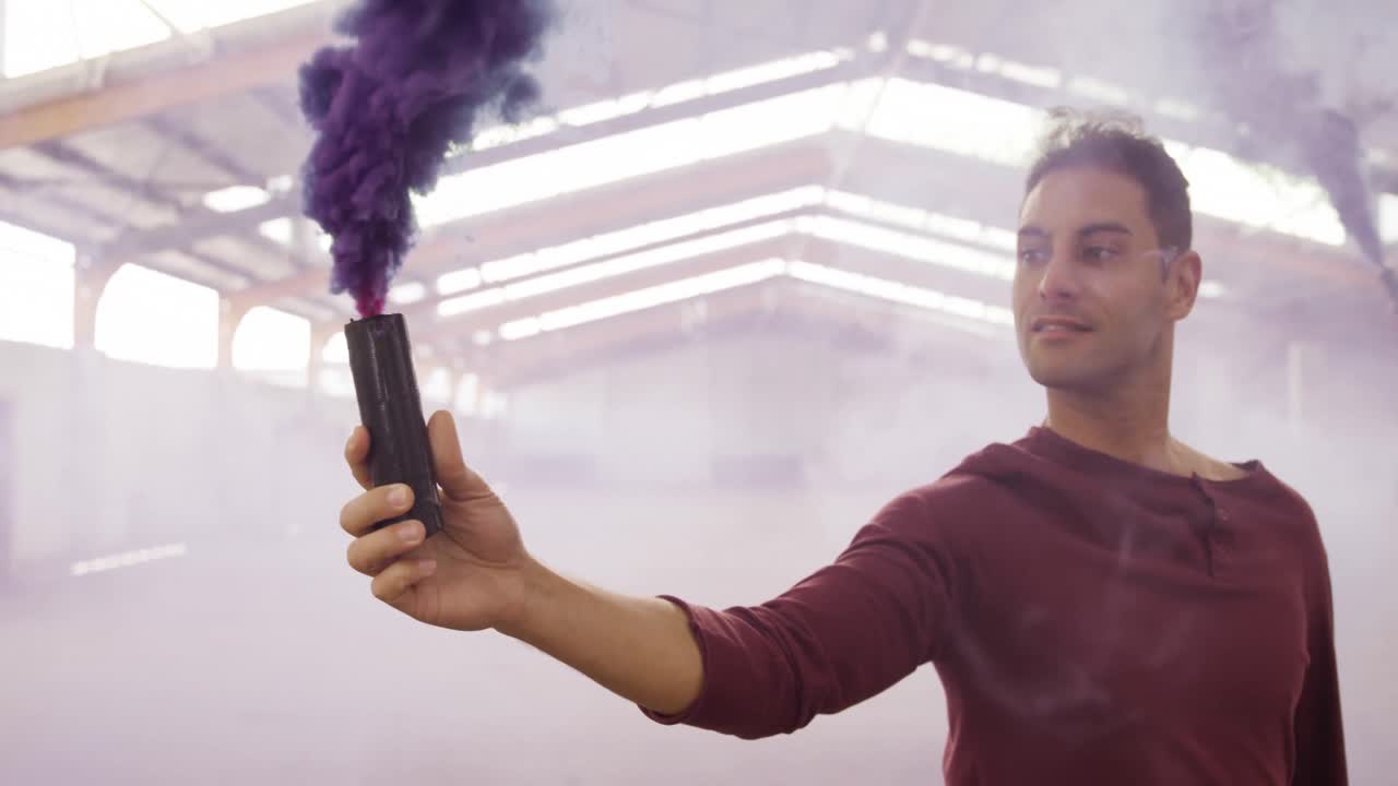 Male dancer in an empty warehouse holding smoke grenade