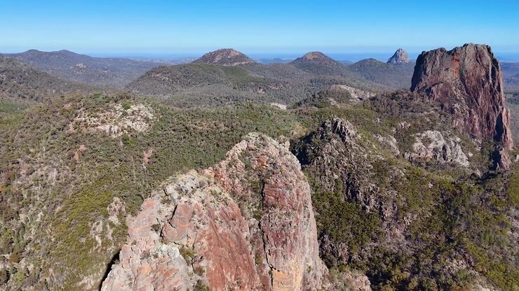 Ripresa con drone che panoramica su antiche cime vulcaniche e foreste di eucalipto nel Parco Nazionale Warrumbungle, Australia.