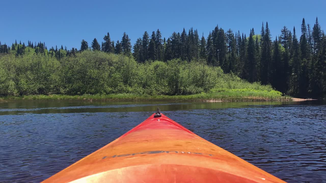A static shot of the bow of a kayak drifting across a river
