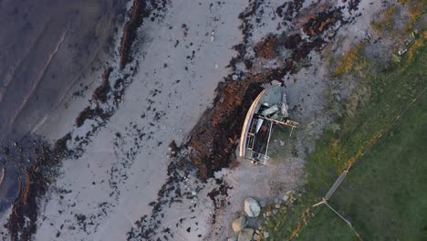 aerial - shipwreck, boat on a beach at sunset in kintyre, scotland, top down rising