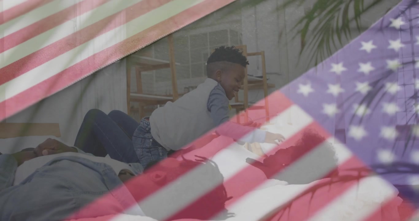 Ragazzo che crea un legame sul divano arrampicandosi sulla donna, mentre un uomo guarda una sovrapposizione della bandiera americana a scopo di marketing.