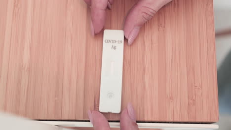 woman's hand put down unused rapid diagnostic test kit on wooden table for covid-19 testing