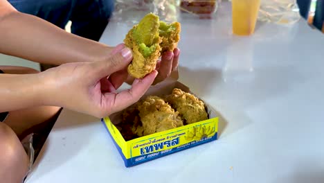 compartir manos y disfrutar de bocadillos fritos de una caja en una mesa de mercado, destacando la comida comunitaria y los sabores vibrantes