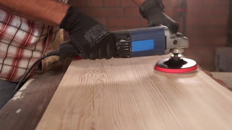 un trabajador está lijando una tabla de madera, preparándose para pintar en una planta