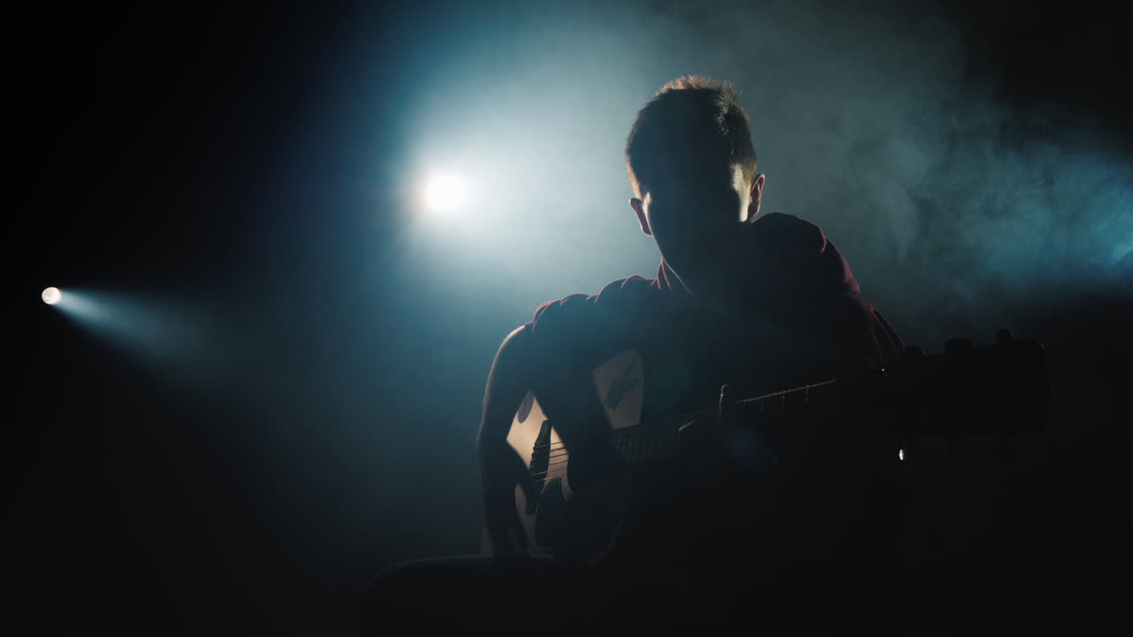 En ung musiker spiller guitar på scenen i rampelyset 4K video