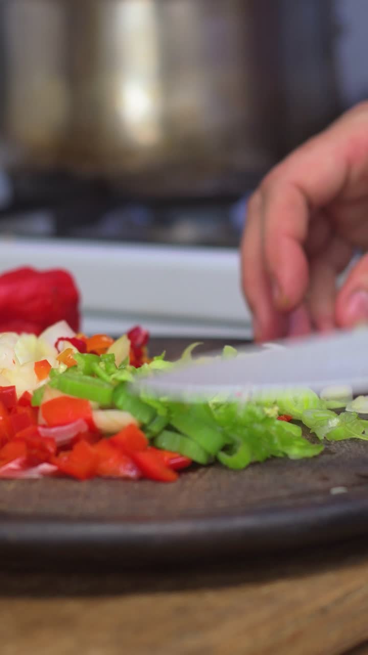 Slicing colorful vegetables on a cutting board with stove in background