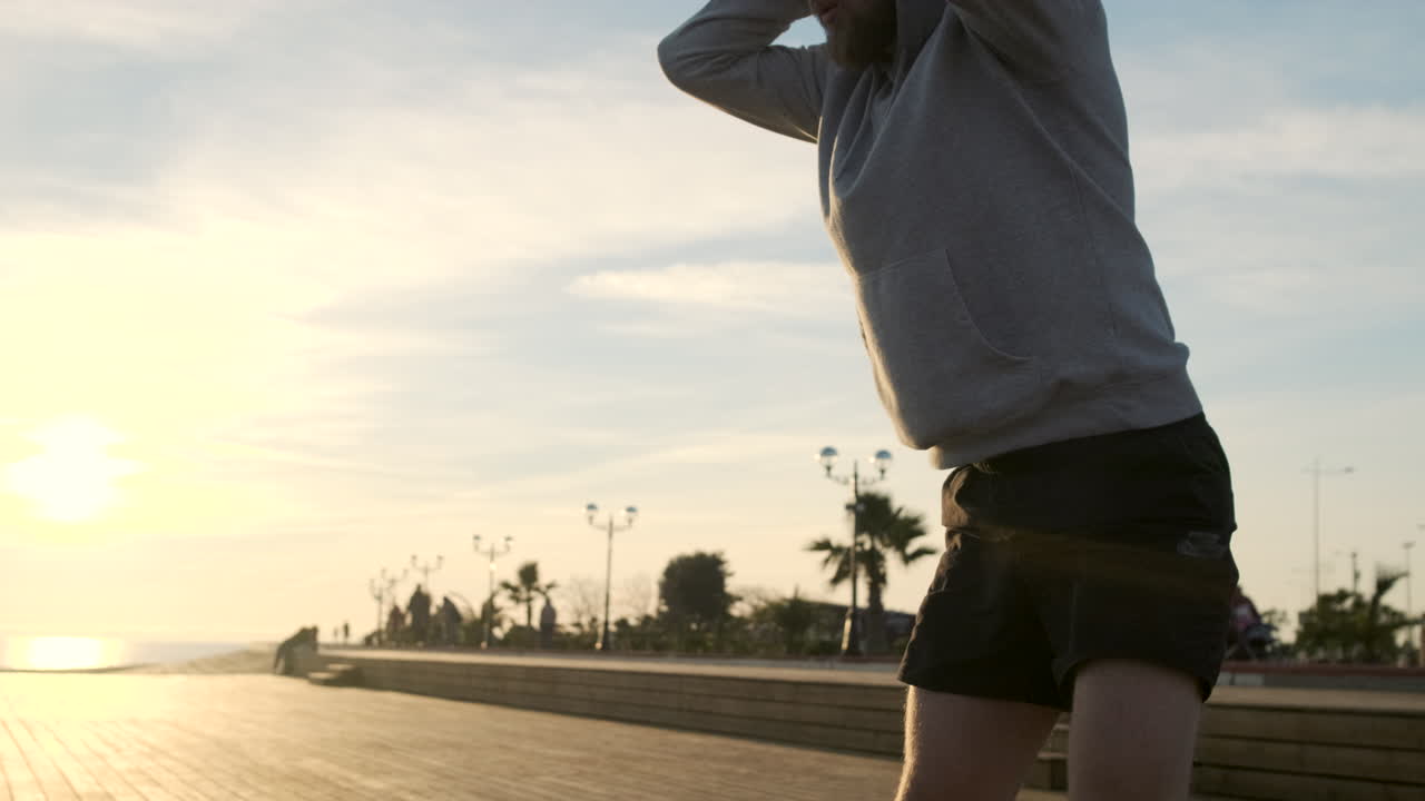 해변에서 해가 지는 동안 스트레칭하는 남자