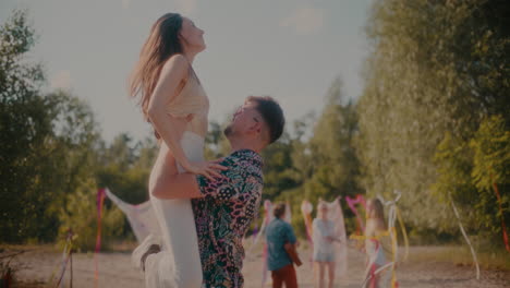 young man lifting girlfriend while dancing bachata at beach
