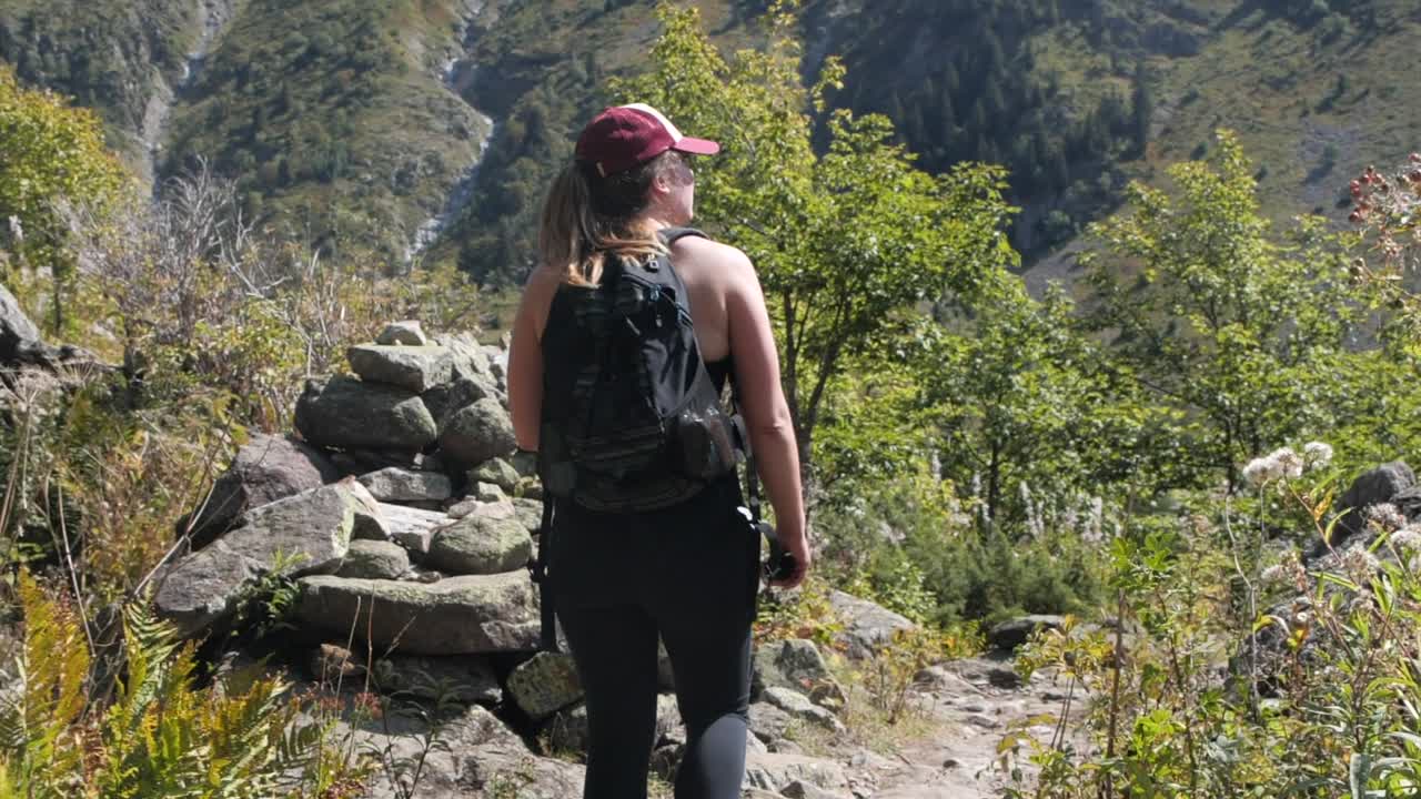 Stunning tracking shot of an attractive Caucasian woman on a mountain hike on a sunny day