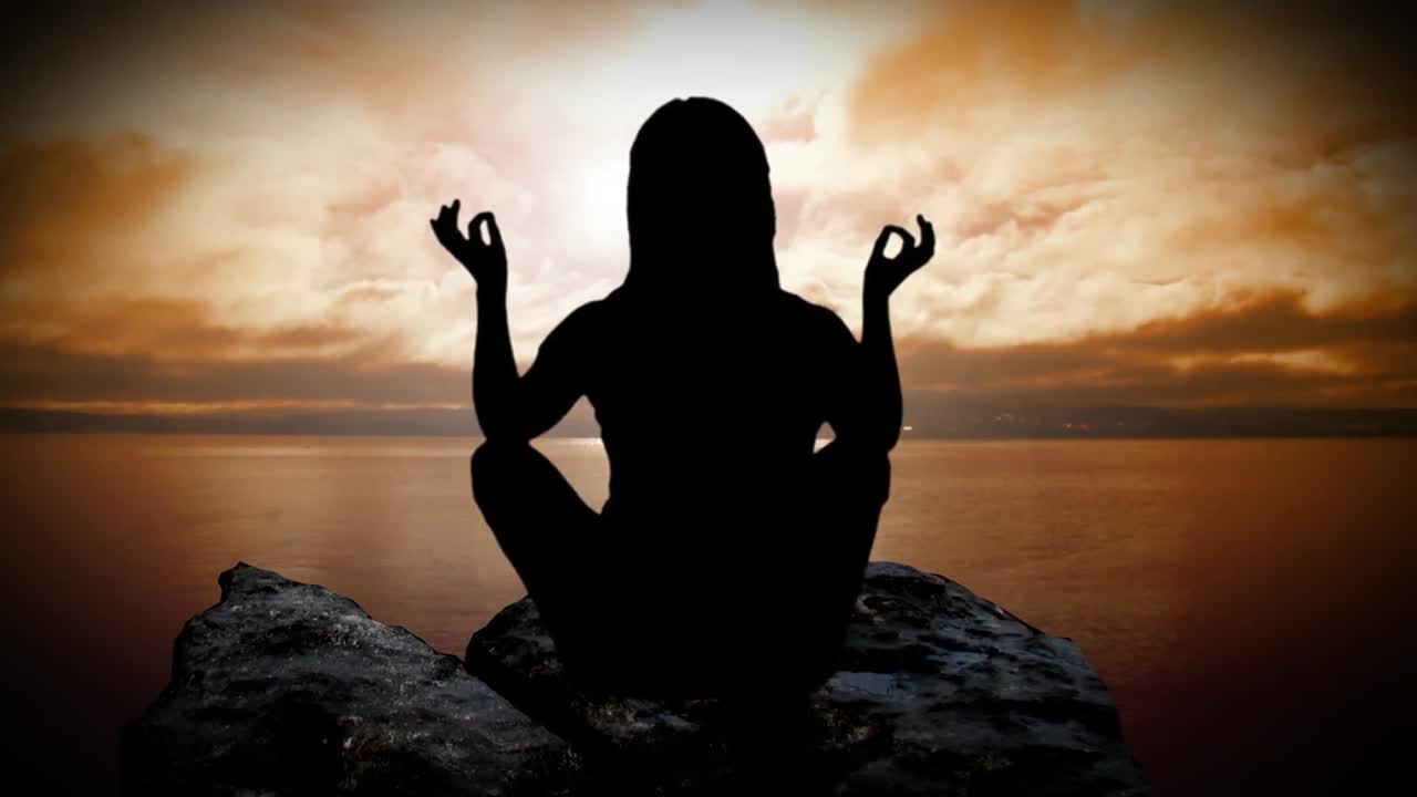 Una mujer meditando al atardecer.