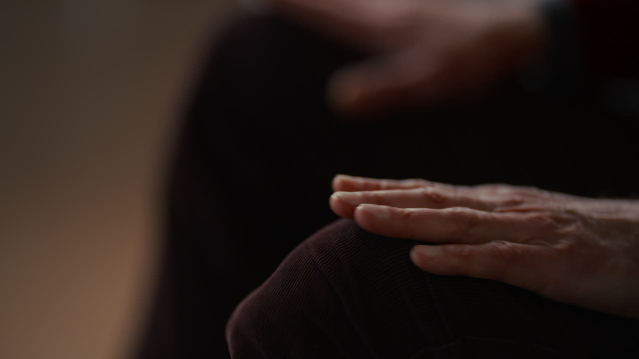 Primo piano delle mani di una persona appoggiate sulle ginocchia in posa pensierosa