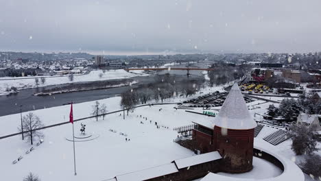 Historical-medieval-castle-of-Kaunas-covered-in-snow-during-strong-snowfall,-aerial-static-view