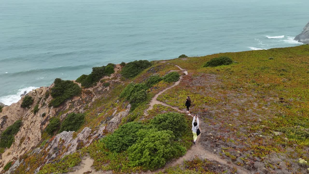 People walking on a cliff path by the ocean