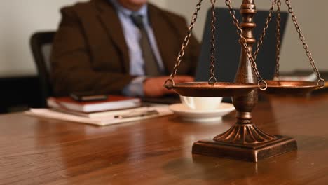 faceless notary working in his laptop at his law firm office, selective focus with a scale in the foreground