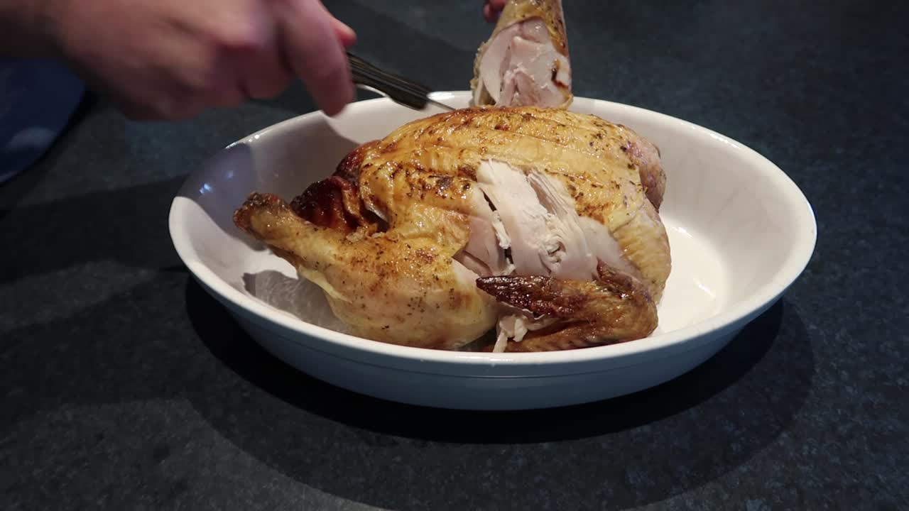 Man cutting or carving a hot roast chicken