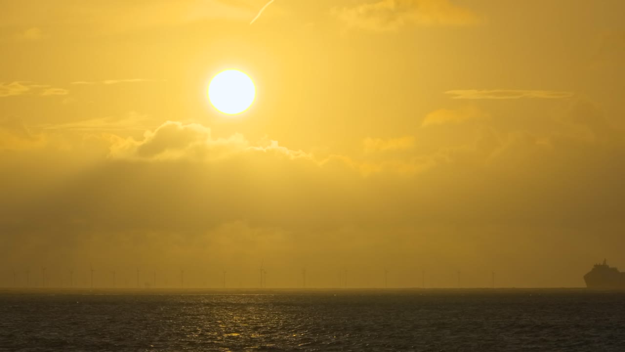 구름 뒤에 해가 지는 두 개의 큰 페리가 지평선에서 서로를 따라 회전하는 풍차와 함께 폭풍의 여름 영어 저녁