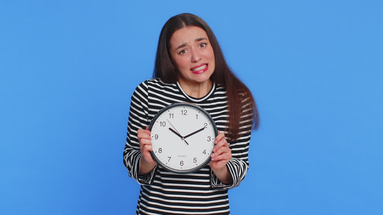 Caucasian woman with anxiety checking time on clock running late to work being in delay deadline