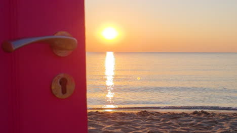 view through an open door to the ocean and sandy beach at sunrise