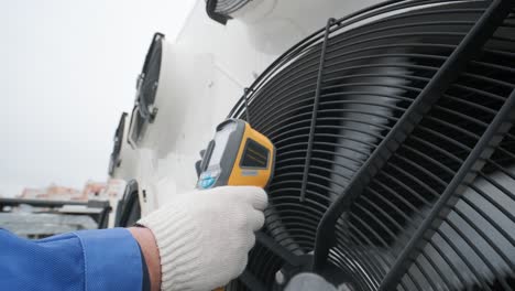 technician uses a thermal imaging infrared thermometer to check the condensing unit heat exchanger