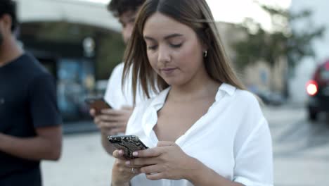 Focused-Caucasian-woman-walking-on-street-with-smartphone