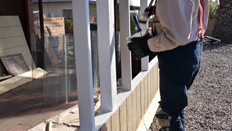 man applying primer paint on wood patio - handheld shot