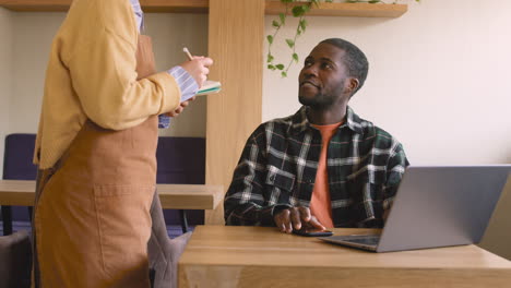 Happy-Man-Sitting-At-Table-And-Ordering-Food-To-Waitress-In-Coffee-Shop