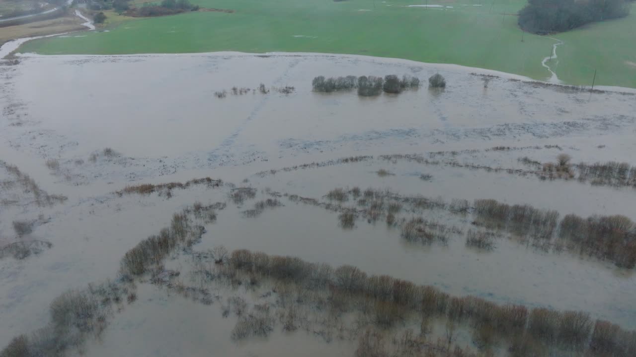 봄에 높은 물의 공중 촬영, 알란데 강 홍수, 갈색과 진 물, 물 아래의 농장, 구름이 많은 날, 넓은 드론, 앞으로 향하는 기울기