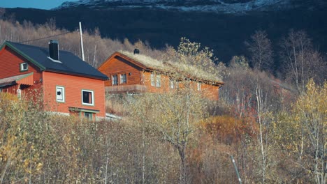 several small brightly colored cottages sit on the forest-covered hill