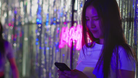 friends meeting woman checking messages on mobile phone in nightclub or funfair 1