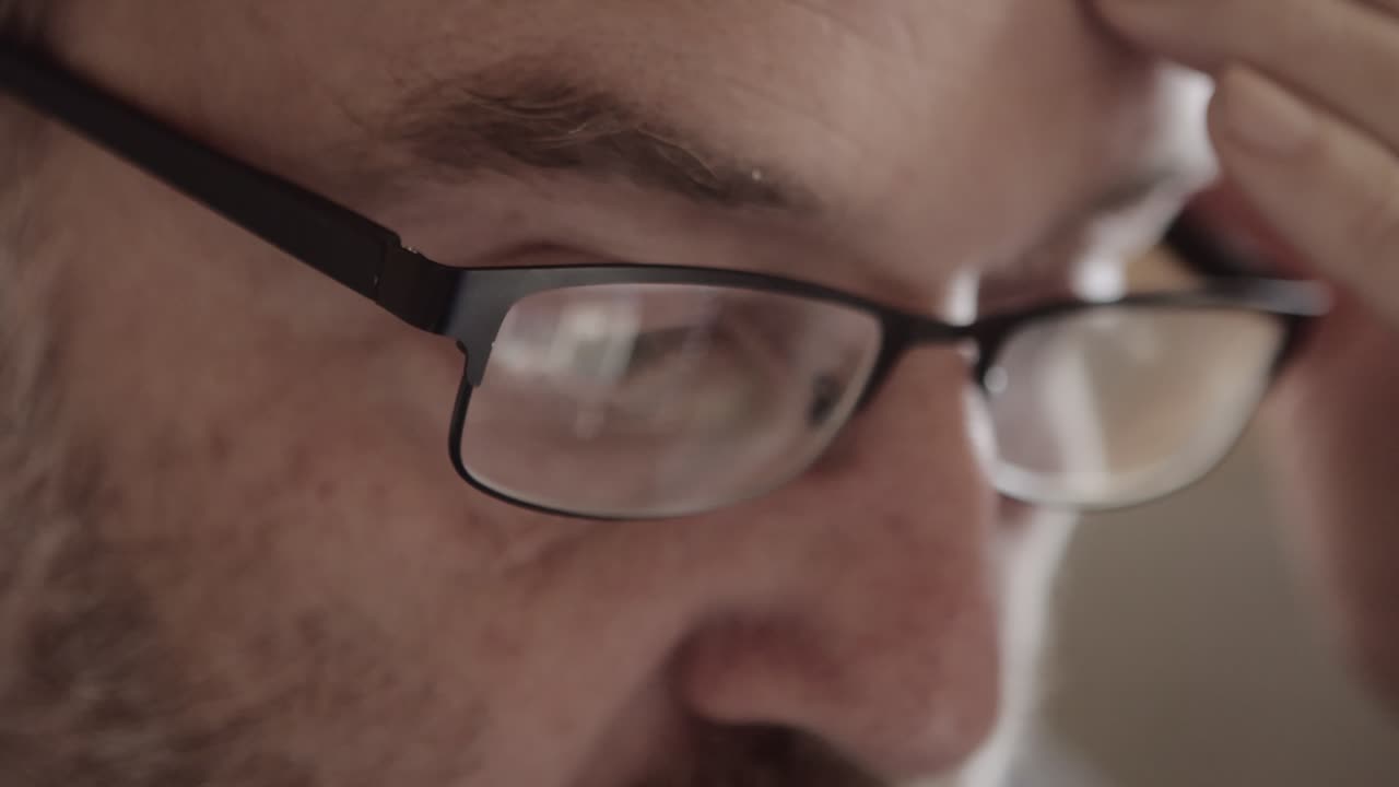 el hombre se desplaza en la pantalla, el reflejo se ve en sus gafas, cierra