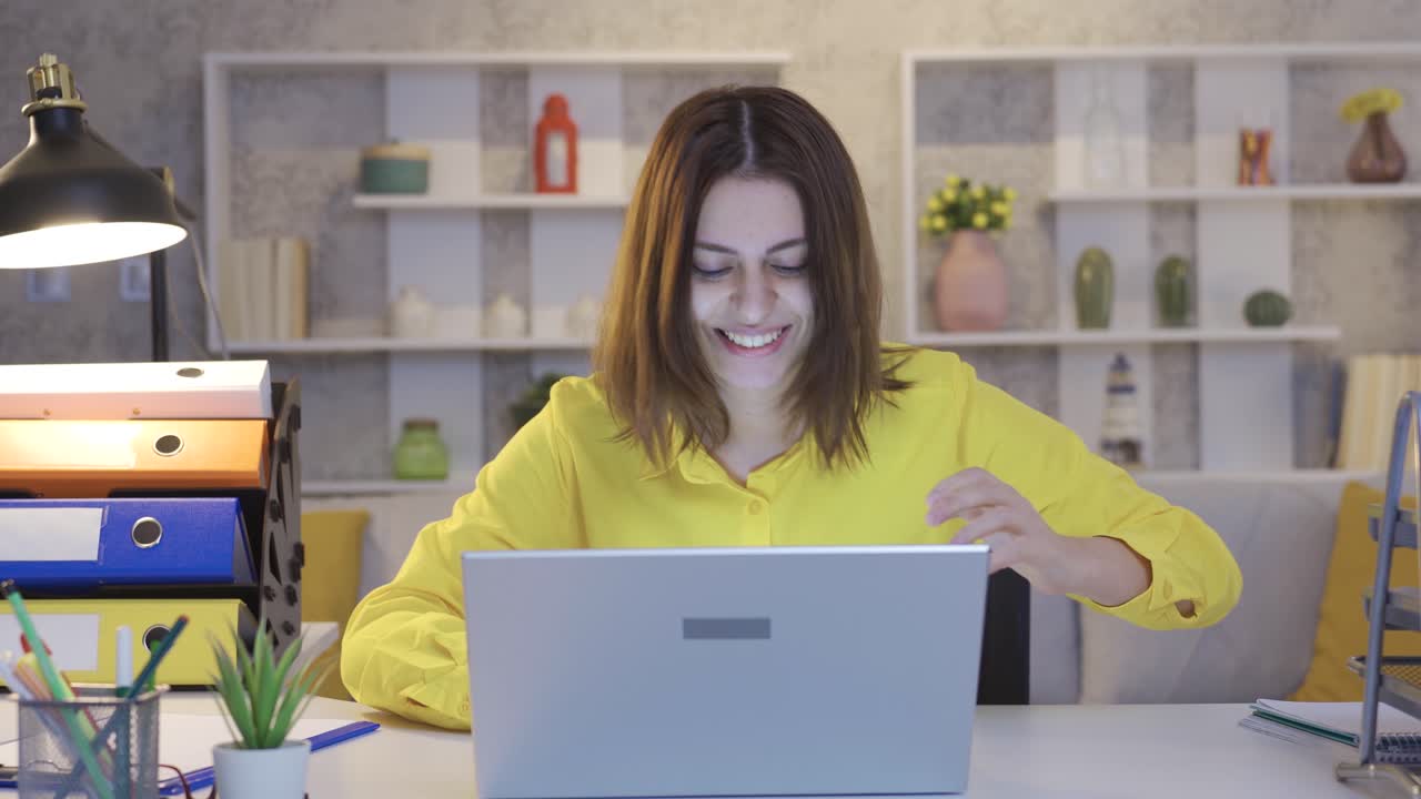 An excited waiting business woman working from home at the computer receives the good news and rejoices.