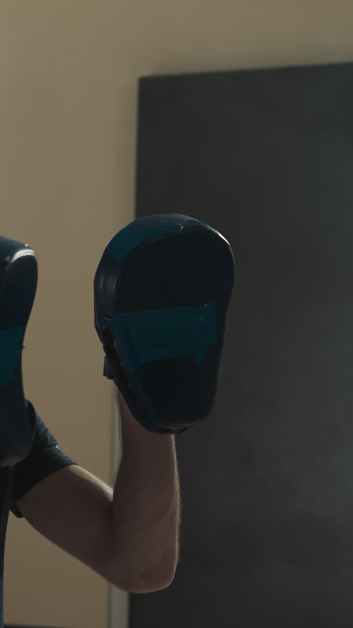 niño golpea almohadillas sostenidas por el entrenador con las manos en el gimnasio. instructor atento entrena a la niña para atacar en la escuela de boxeo en cámara lenta. ocio saludable