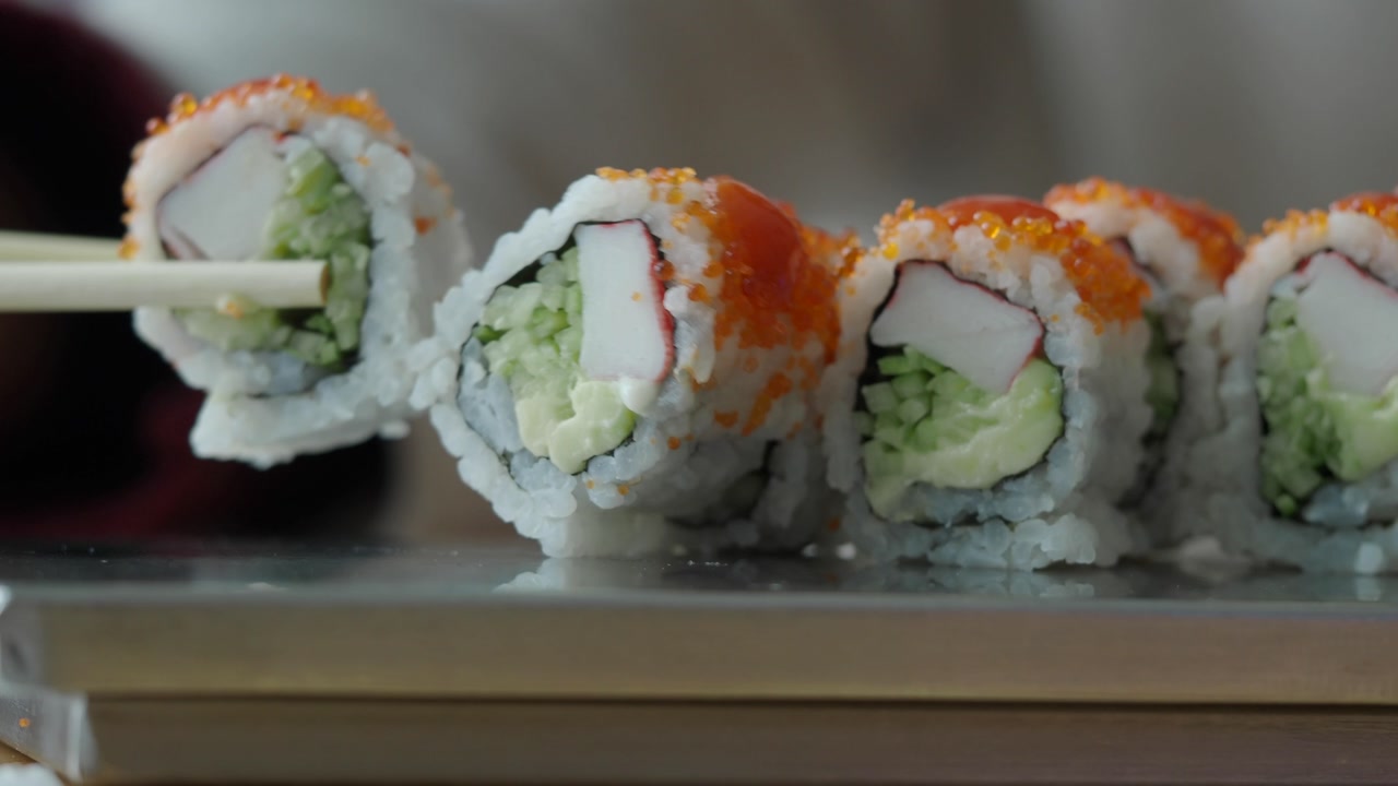Chopsticks Picking Up a Fresh California Sushi Roll