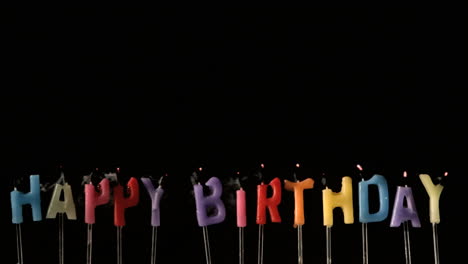 colourful happy birthday candles being extinguished