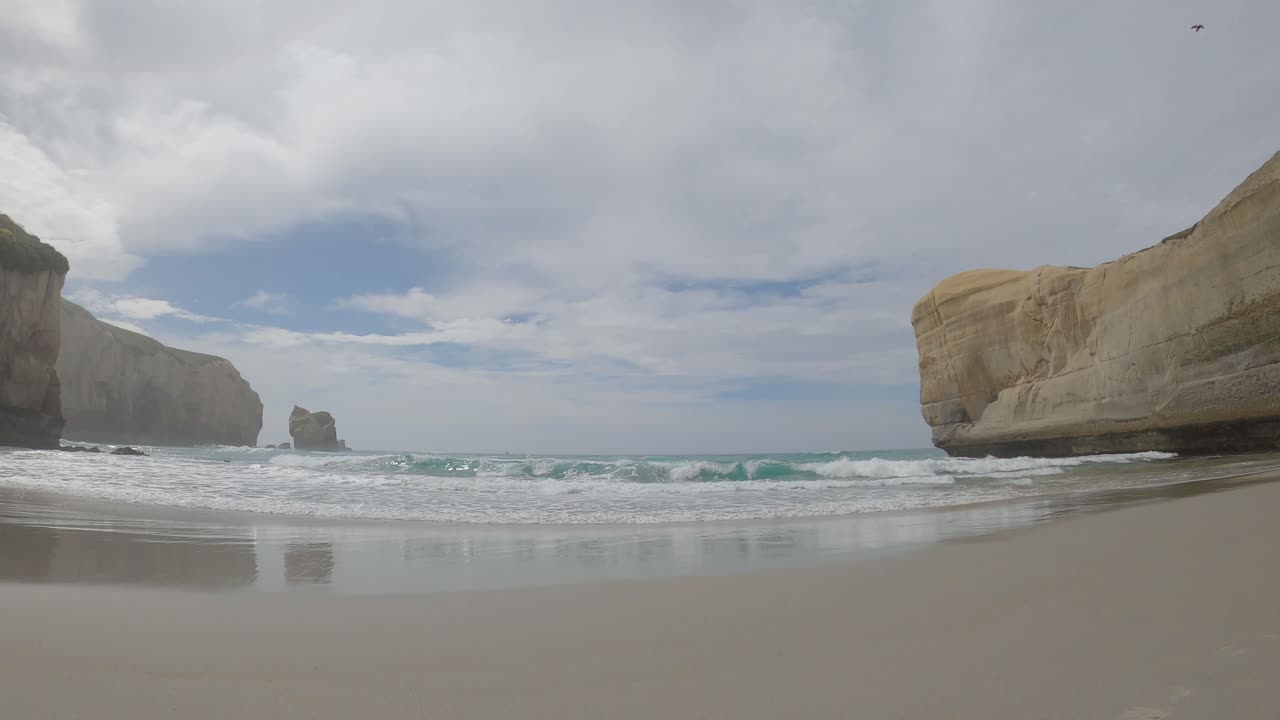 toma panorámica de arena hermosa, playa aislada e increíbles acantilados de arenisca - vía de la playa del túnel, dunedin